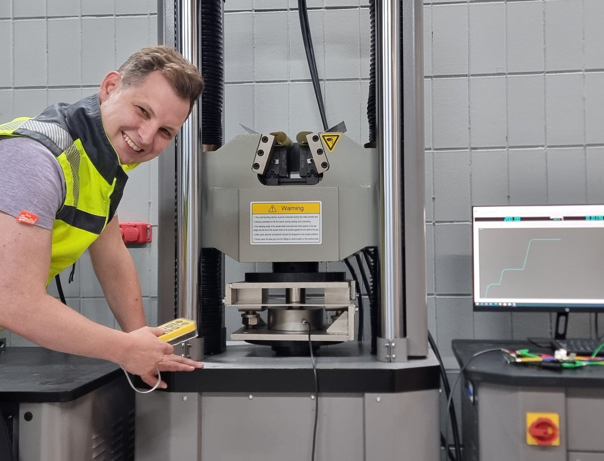 Mitarbeiter von octogon in Warnweste an der Prüfmaschine im Kalibrierlabor